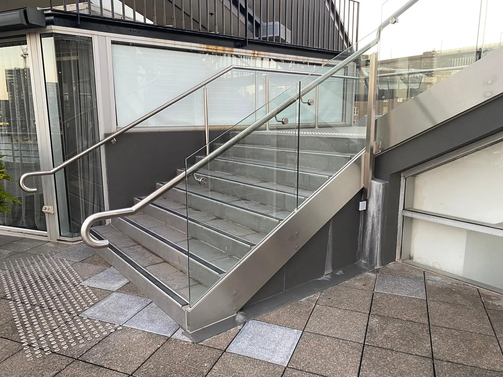 Exterior stair with a stainless and glass balustrade and a curved handrail.