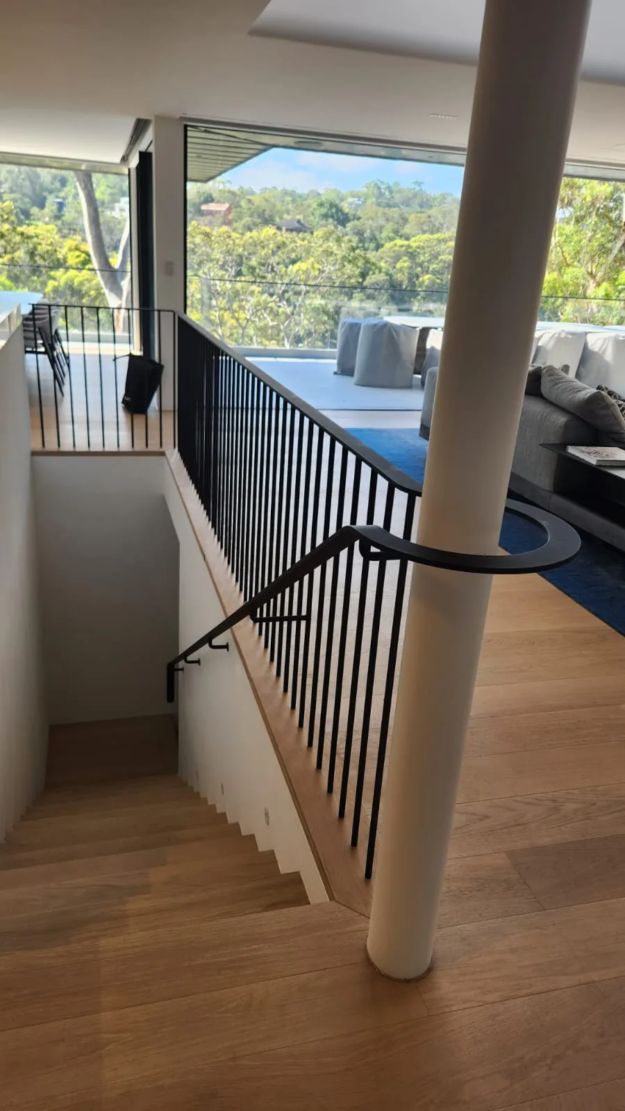 Black steel balustrade and round column at a stair void with a harbour outlook.