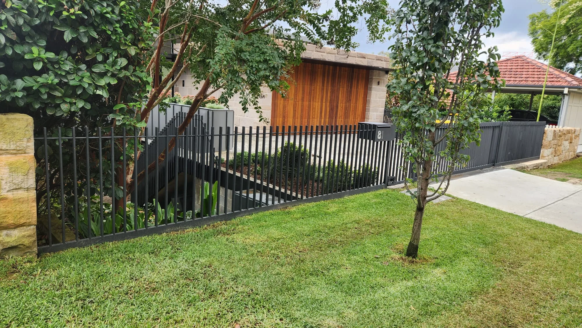 Black steel bar front fence combined with timber cladding.