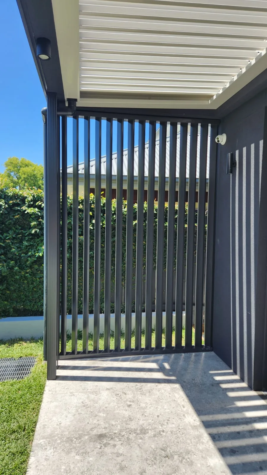 Aluminium vertical-batten privacy screen and gate to a breezeway.