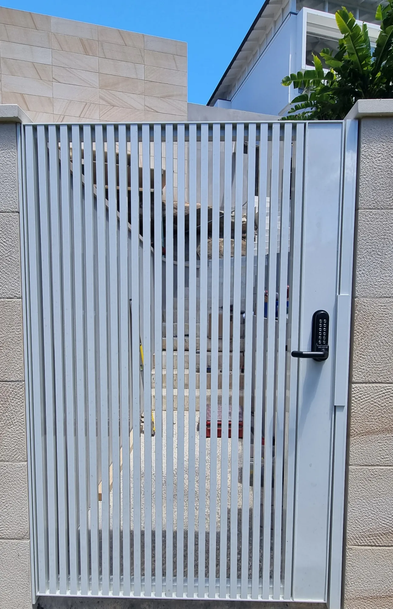 Aluminium vertical-batten pedestrian gate with keypad entry, matching the driveway gate.
