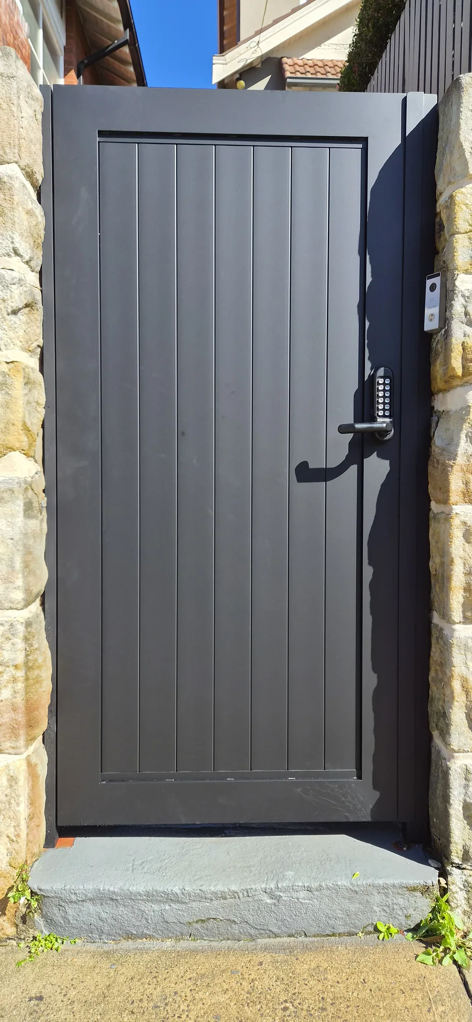 Dark aluminium horizontal-slat garage and driveway gate.