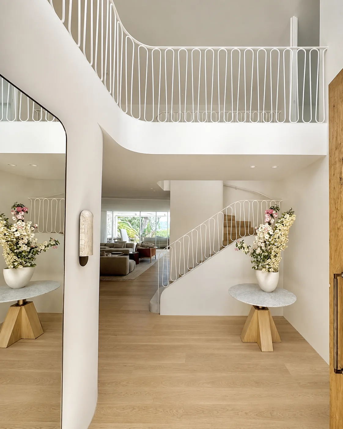 Curved staircase and upper-landing balustrade in a double-height foyer.