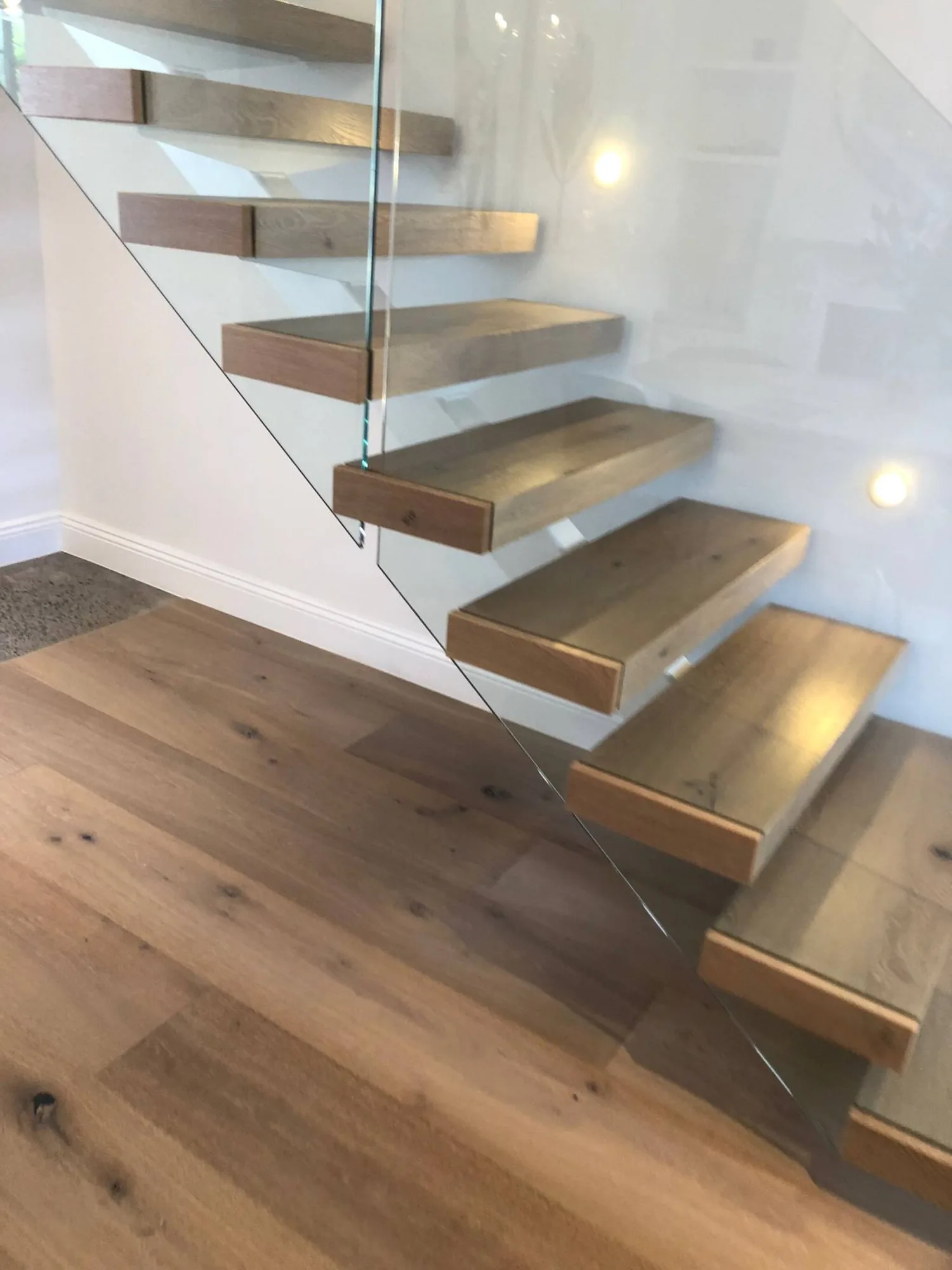 Floating timber-tread staircase with a frameless glass balustrade.
