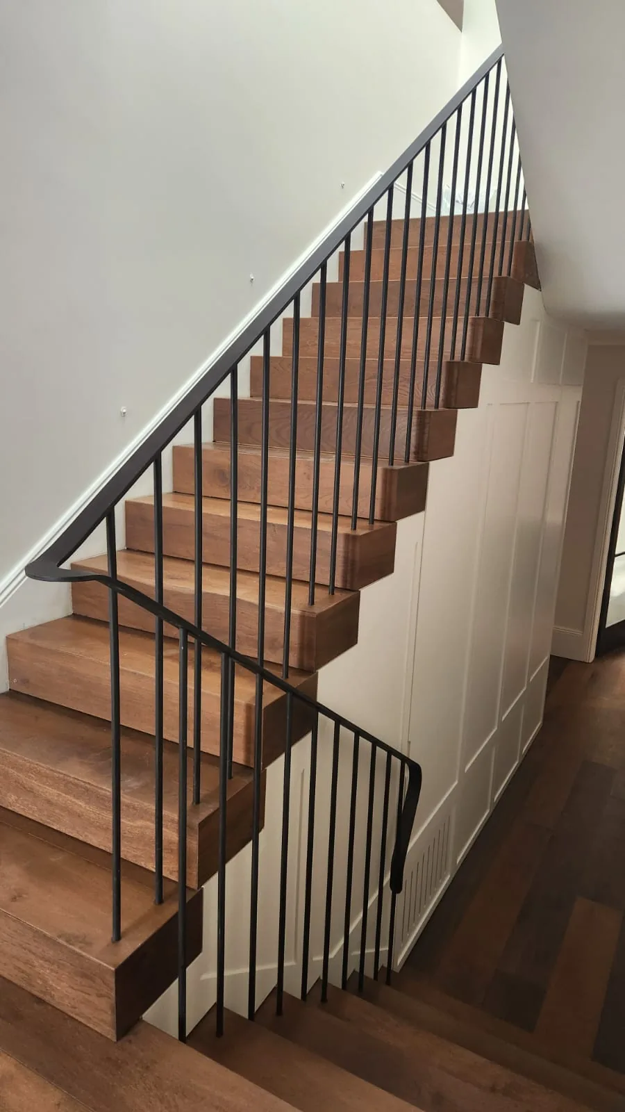 Interior timber staircase with a black steel balustrade, viewed from above.
