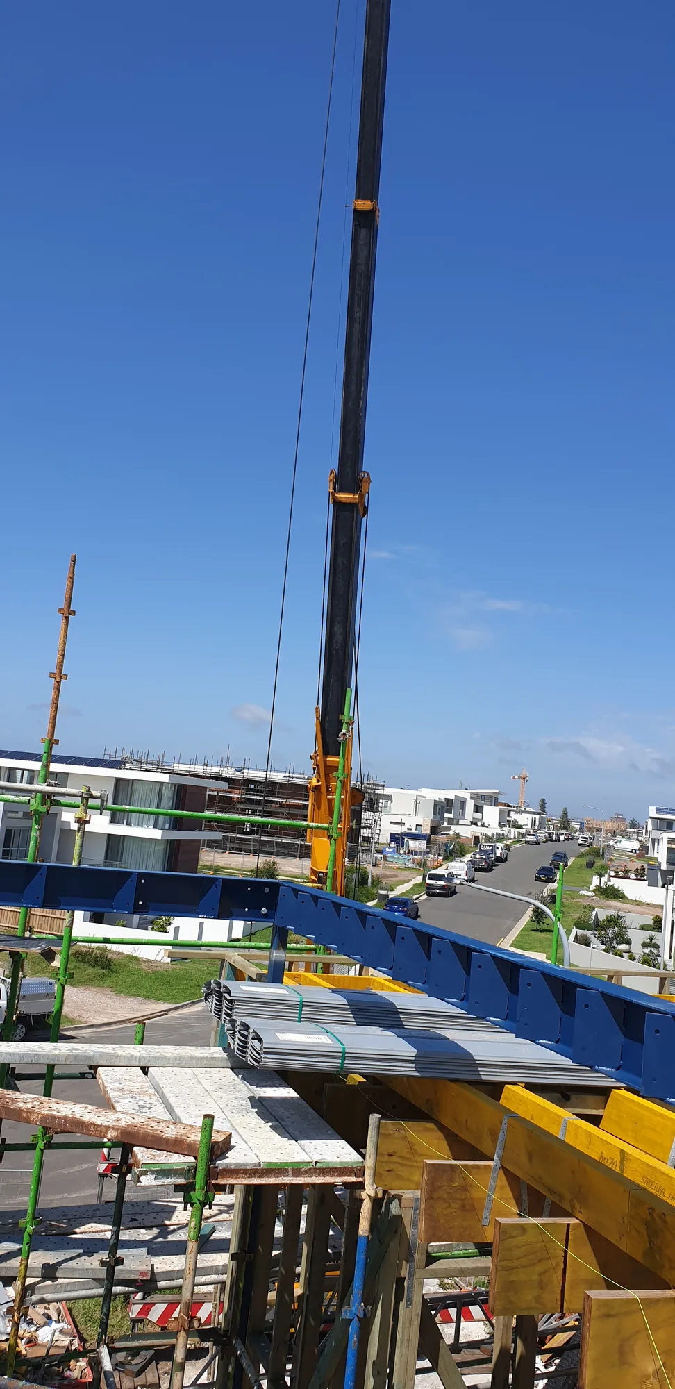 Structural steel beam being craned into position on site.