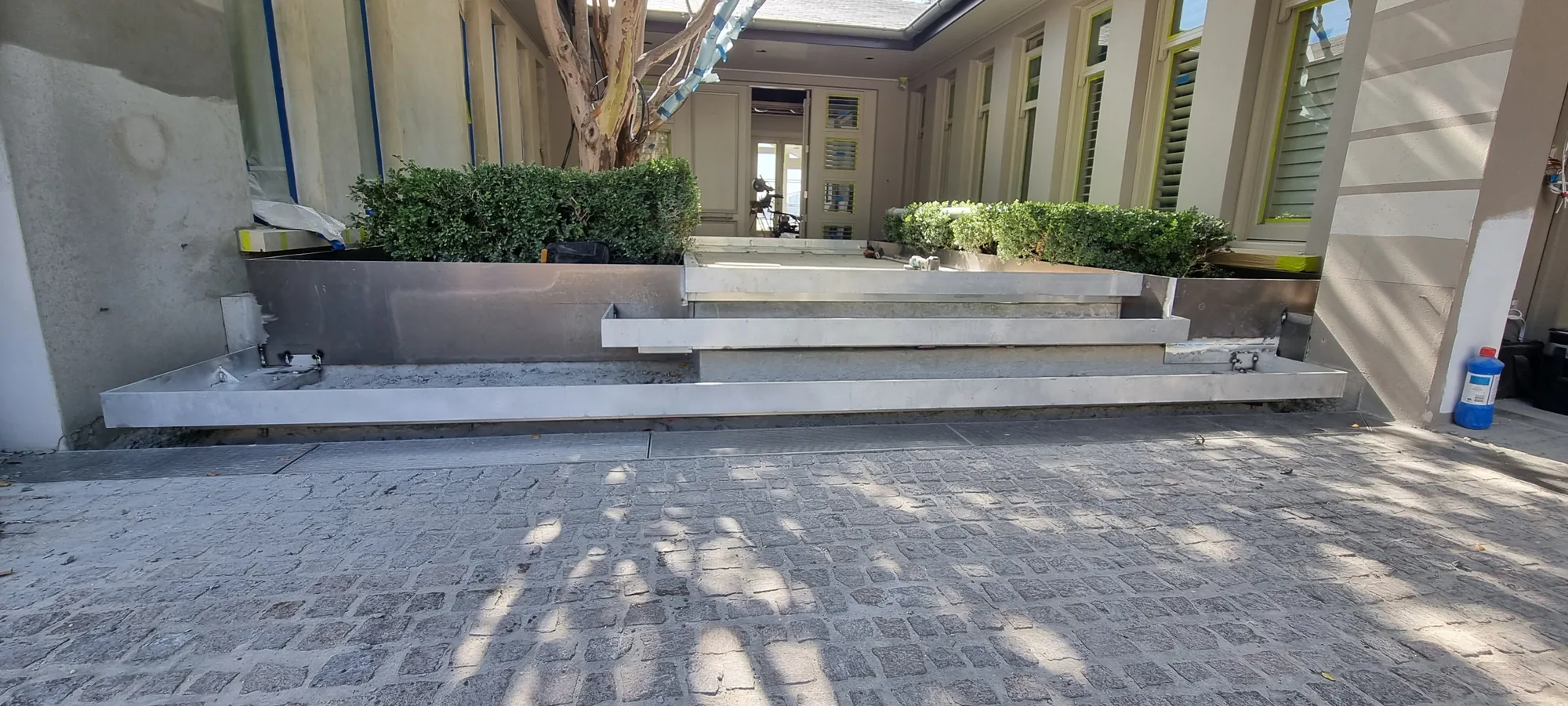 Stainless and steel planter boxes and steps to a residential courtyard entrance.