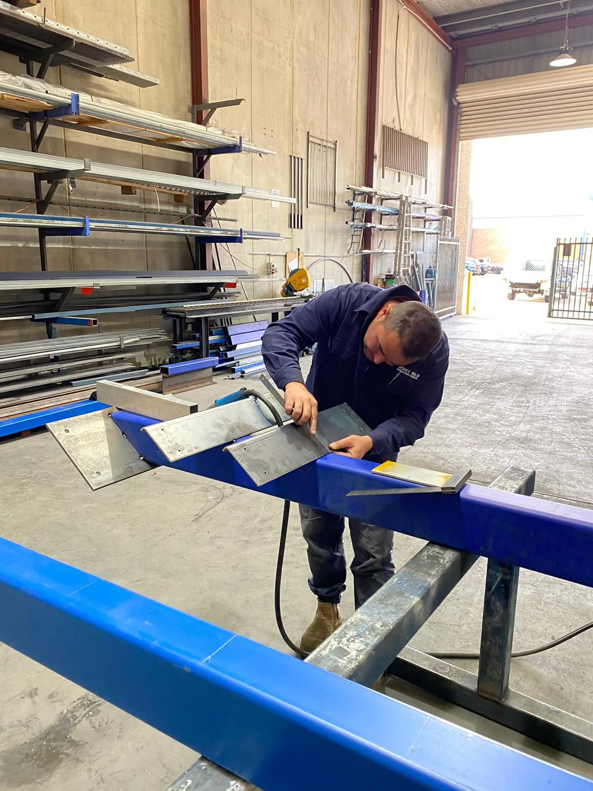 Fabricating long blue steel stair stringers on trestles in the workshop.