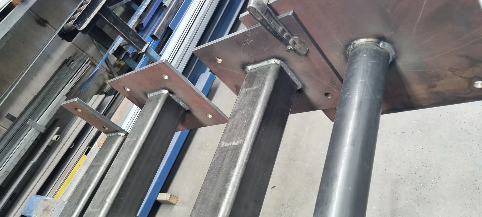 Close-up of a welded steel base plate and post bracket in galvanised finish.