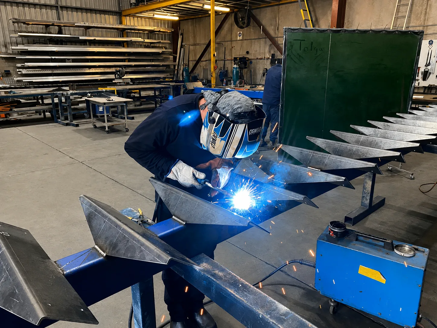 MIG welding a steel stair stringer with a live arc and sparks in the workshop